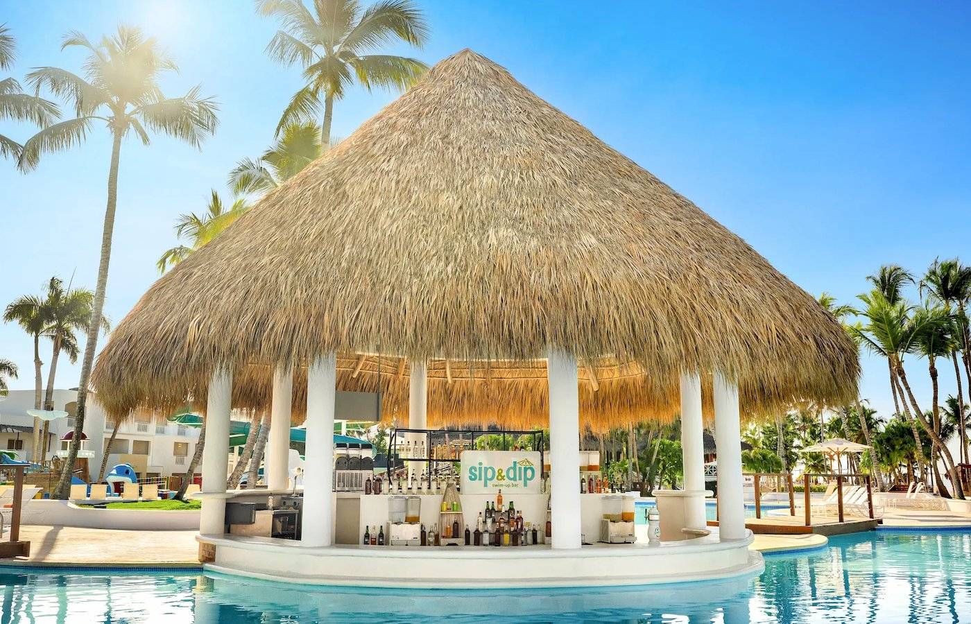 Strandbar im Pool des Sunscape Dominicus La Romana mit Strohdach und Getränken.