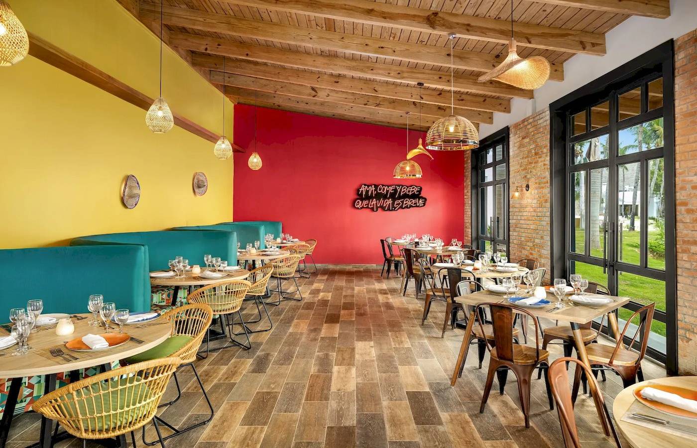 Innenbereich des Restaurants Sunscape Dominicus La Romana mit bunten Wänden, Holzboden und Tischdekoration.