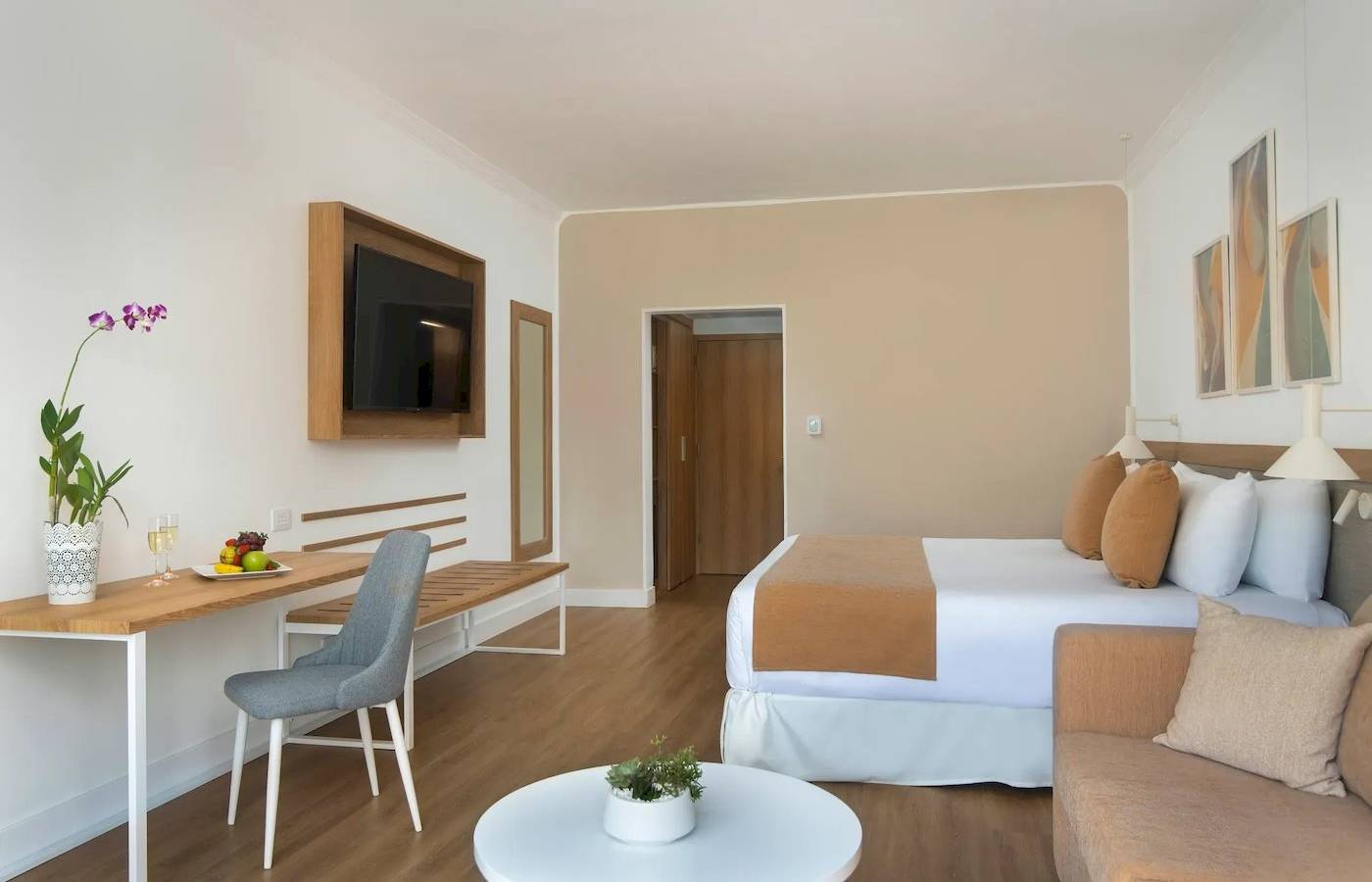 Innenansicht eines Zimmers im Sunscape Dominicus La Romana Hotel mit einem Bett, Schreibtisch, Sofa und Fernseher.