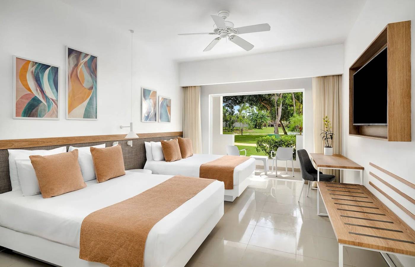 Doppelzimmer im Sunscape Dominicus La Romana mit zwei Betten, Klimaanlage, Fernseher und Fenster zur Terrasse.