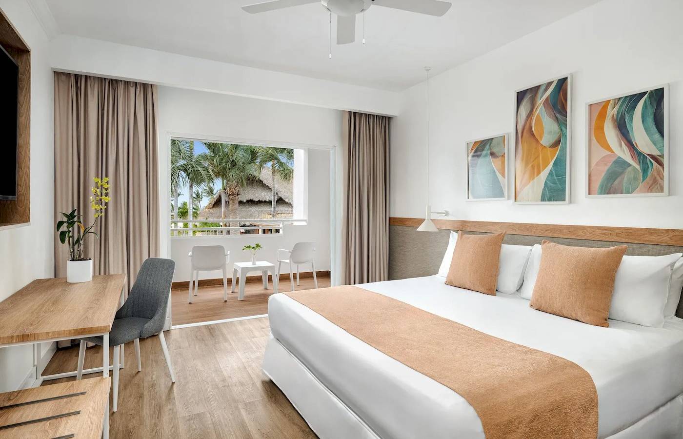 Innenansicht eines Hotelzimmers im Sunscape Dominicus La Romana mit einem Bett, Tisch, Stühlen und einer Terrassentür.