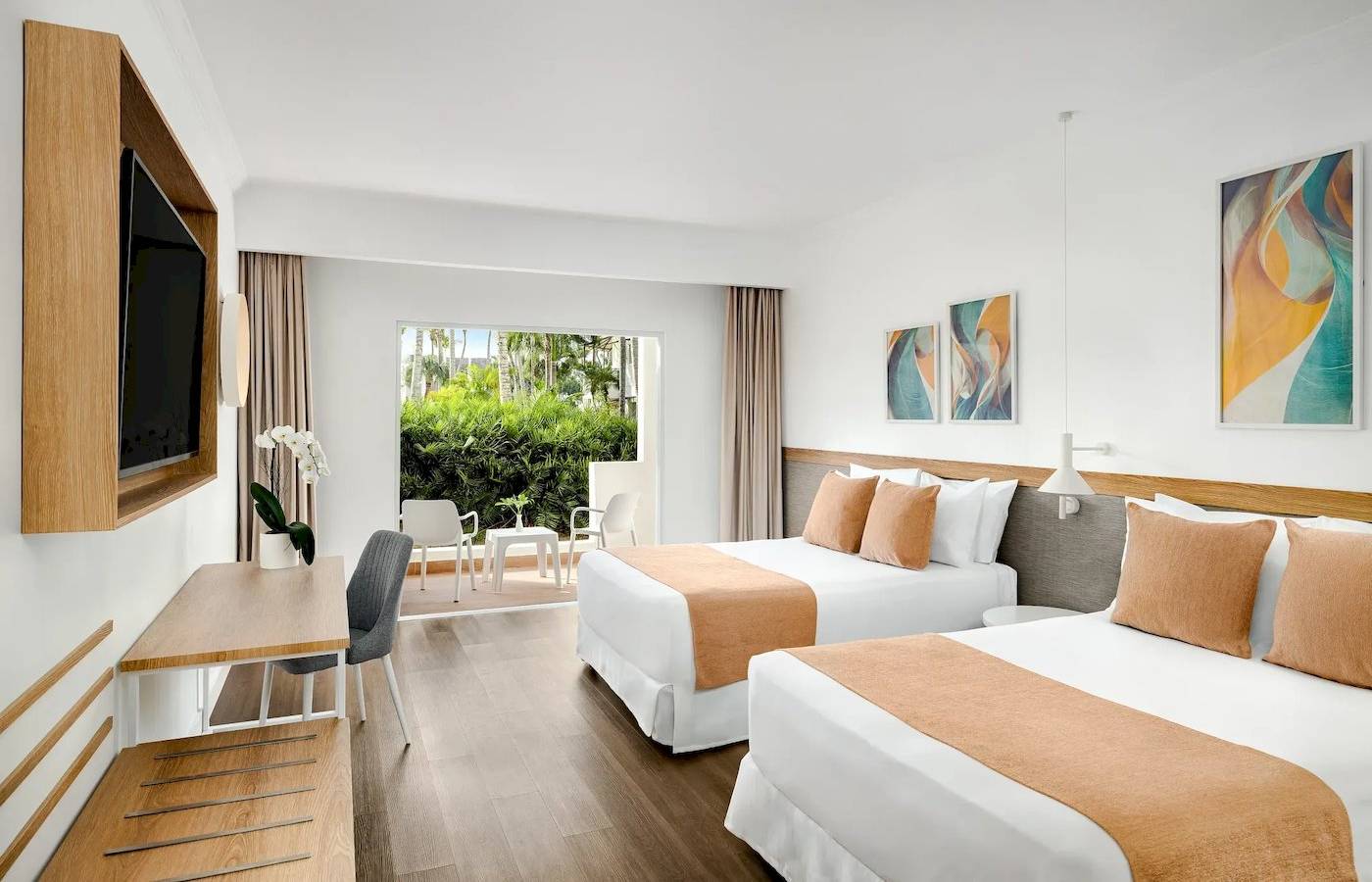 Innenansicht eines Hotelzimmers von Sunscape Dominicus La Romana mit zwei Betten, Schreibtisch und Fernseher.