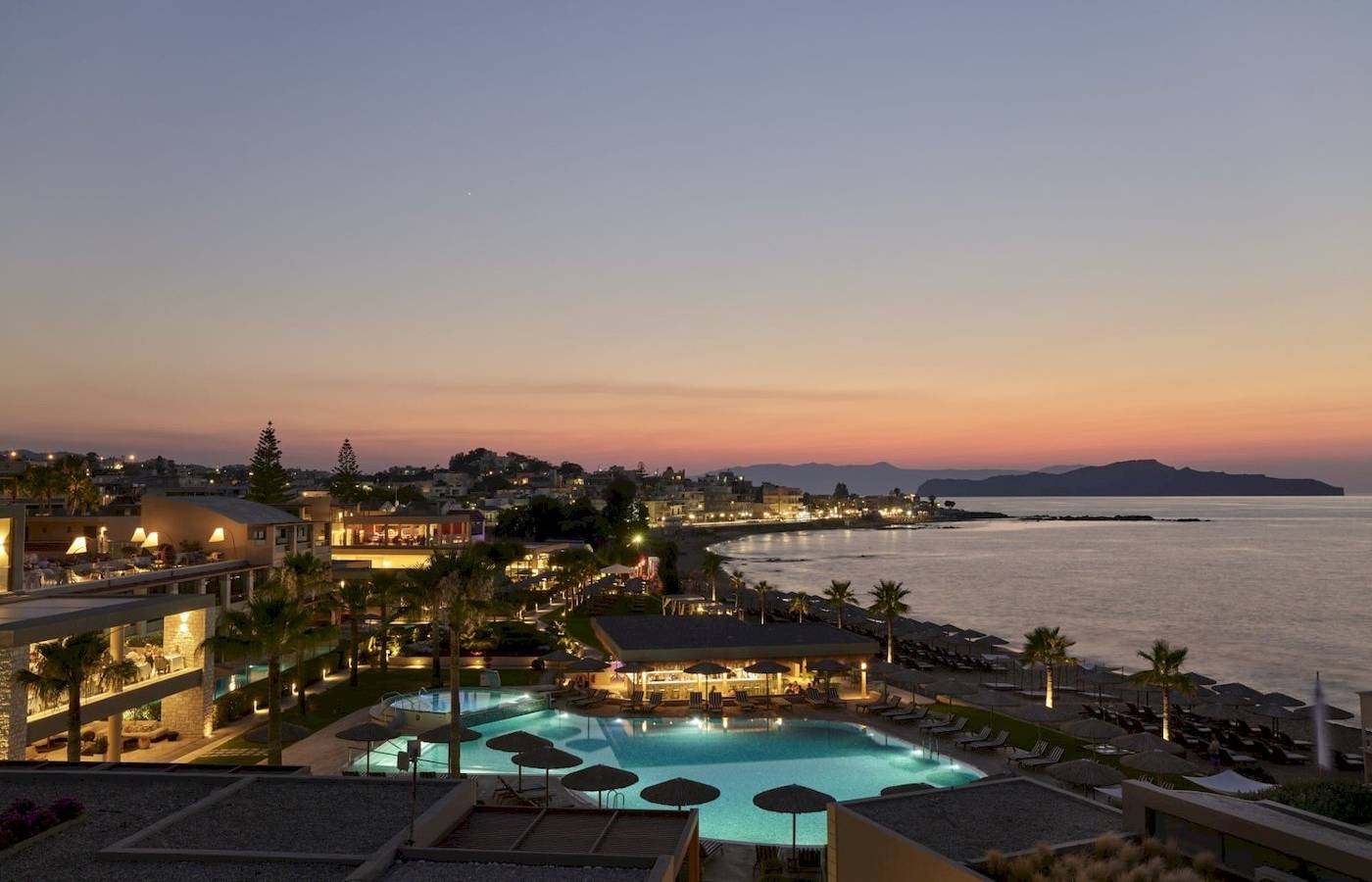 Abendlicher Blick auf das Atlantica Kalliston Resort mit Pool, Bars und Strand.