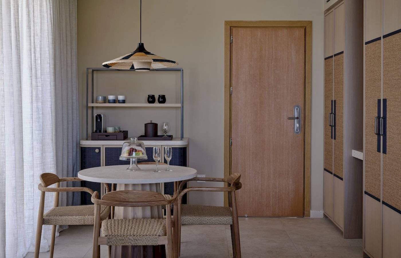 Esstischbereich im Atlantica Kalliston Resort mit modernem Design, Holzmöbeln und einer offenen Küche im Hintergrund.