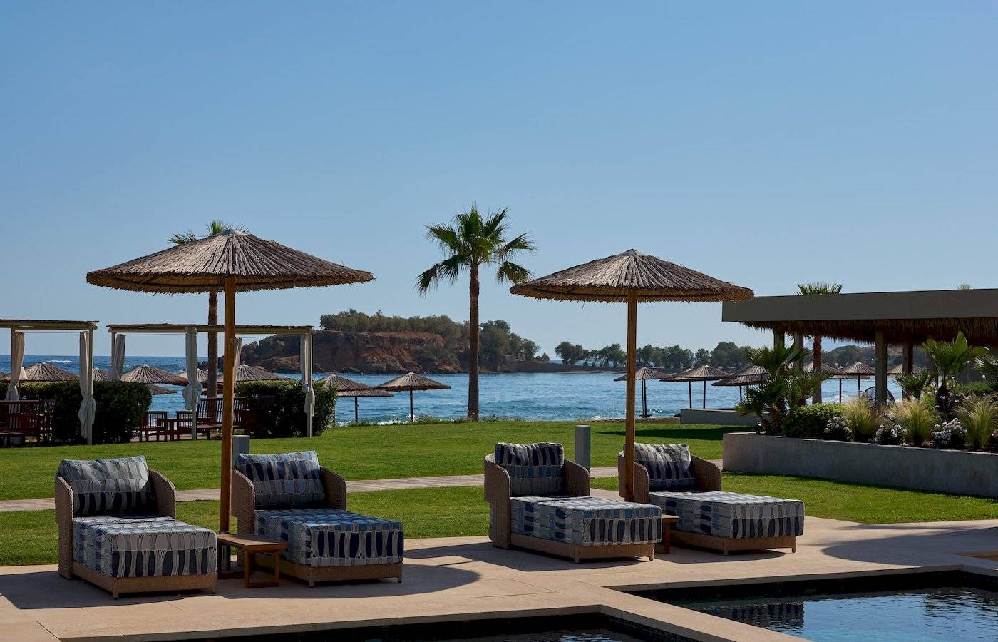 Lounge-Sessel am Pool des Atlantica Kalliston Resorts mit Blick auf das Meer.