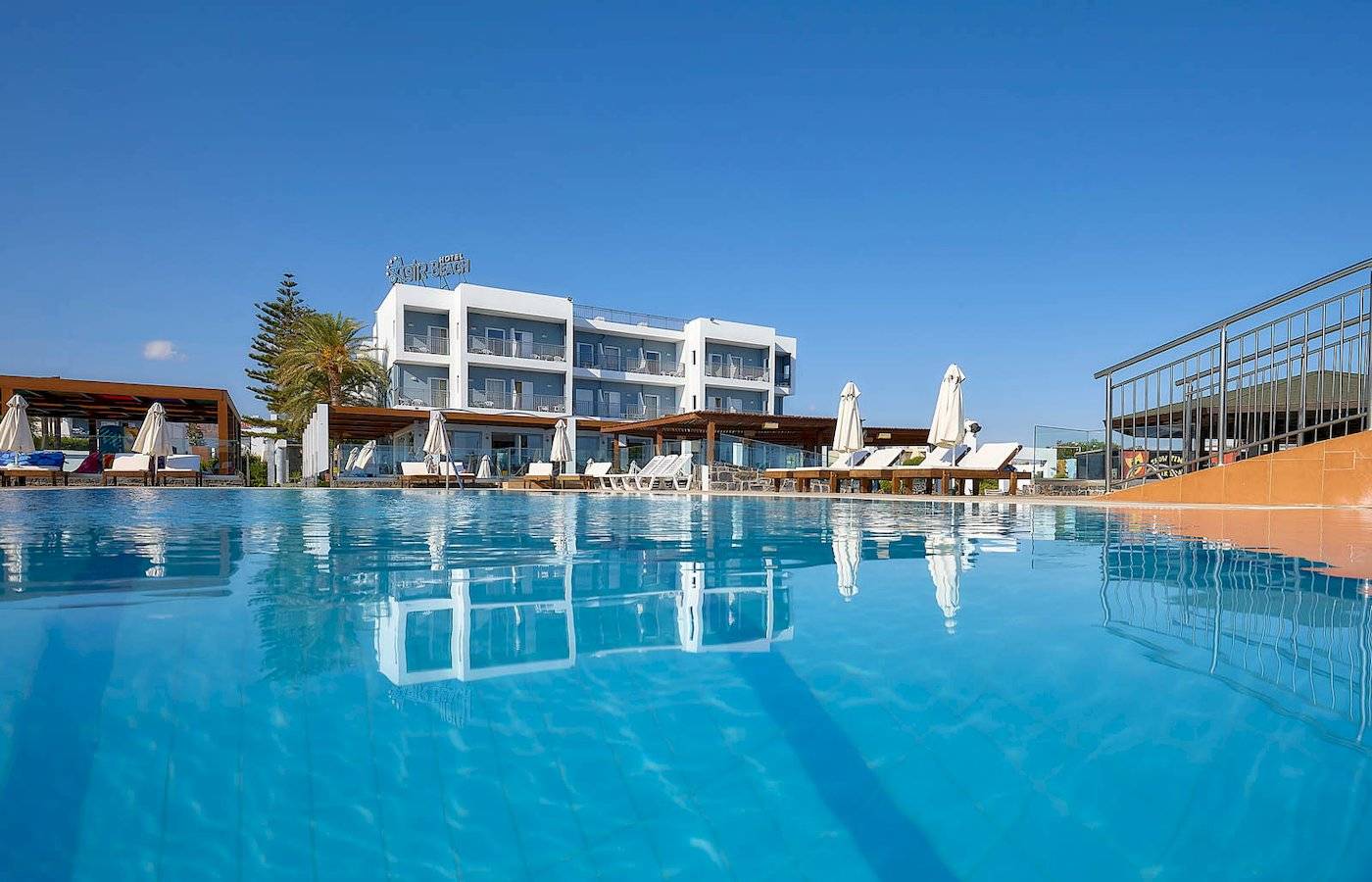 Außenpool des Astir Beach Hotels auf Kreta mit weißen Liegen und Sonnenschirmen.