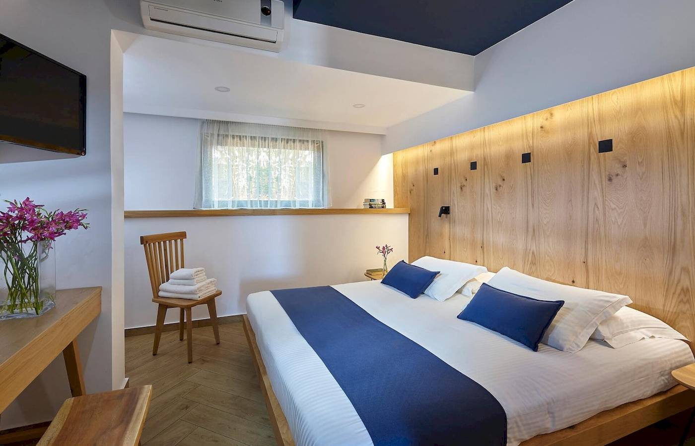 Schlafzimmer im Arminda Hotel & Spa mit einem Bett, Holzwand, Fernseher, Stuhl, und Tisch.