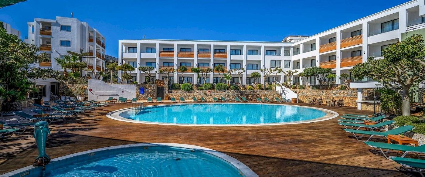 Außenpool mit Sonnenliegen und Blick auf das Arminda Hotel & Spa.