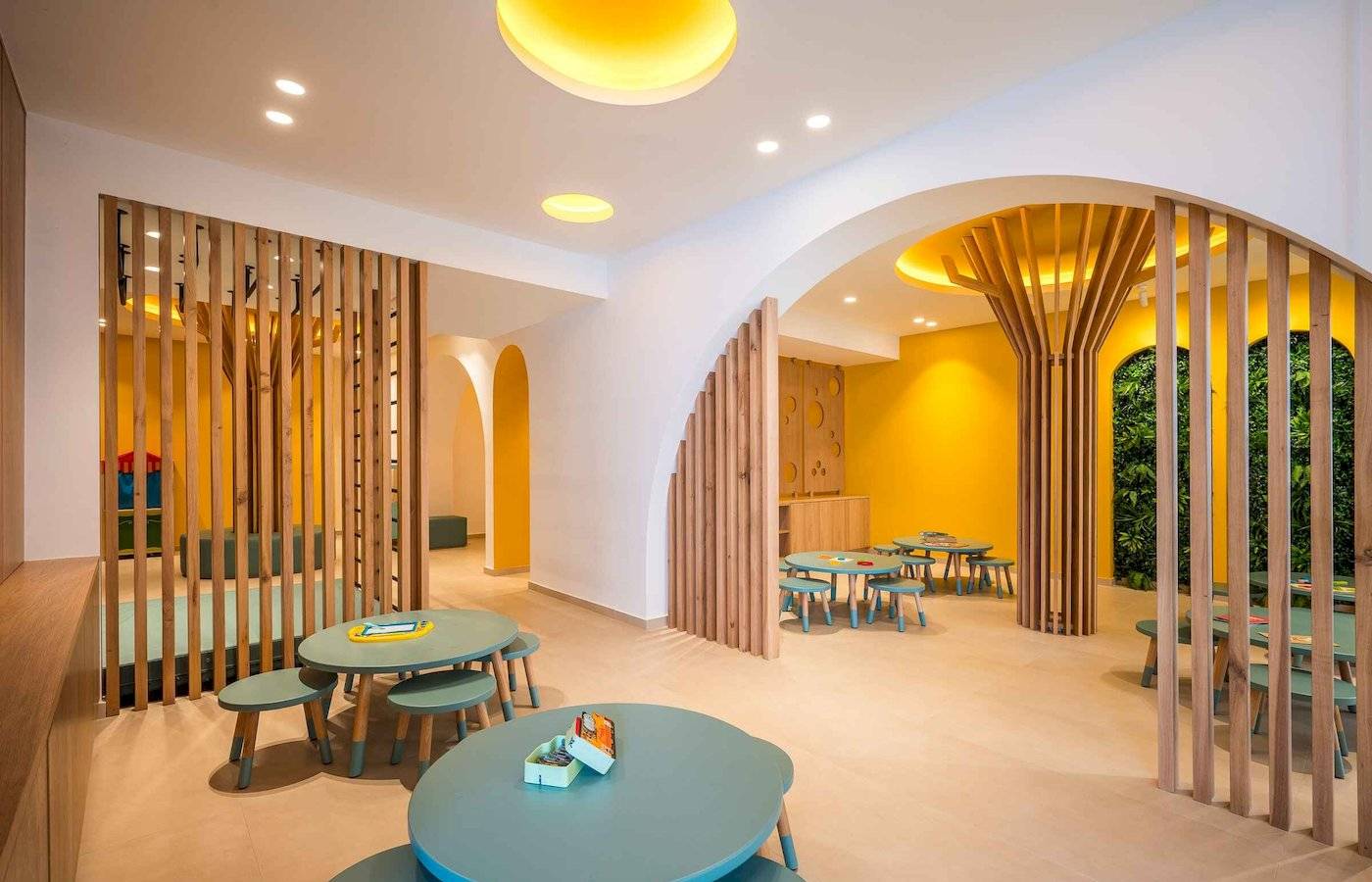 Innenbereich des Arminda Hotel & Spa mit blauen Tischen, hölzernen Trennwänden und gelben Wänden.