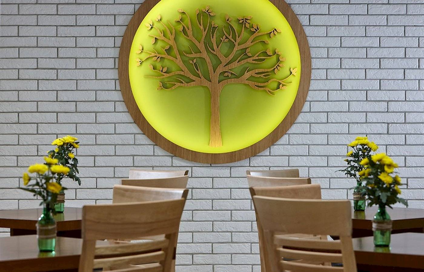 Arminda Hotel & Spa Innenraum mit Baum Wandkunst und Tischen mit Blumenvasen.