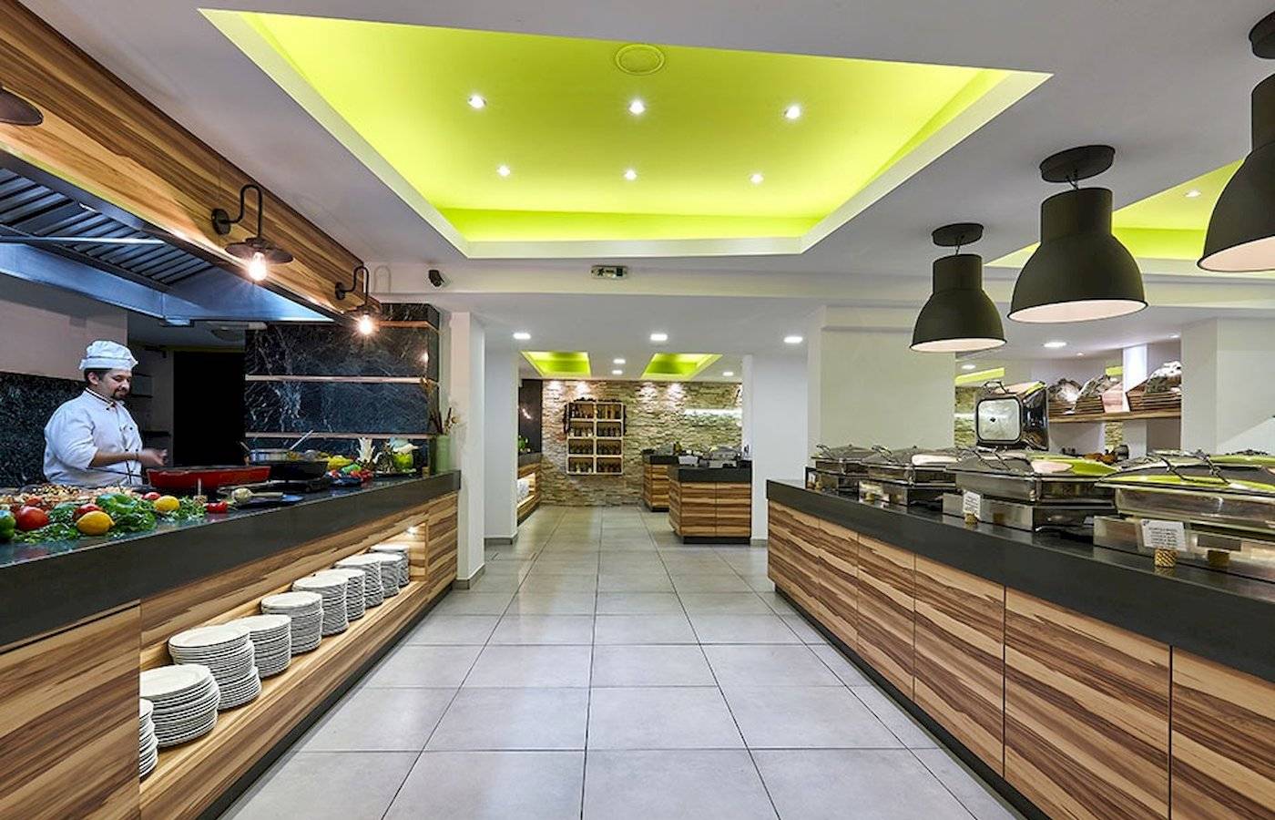 Innenansicht des Restaurants des Arminda Hotel & Spa mit einem Koch, der Gerichte zubereitet.