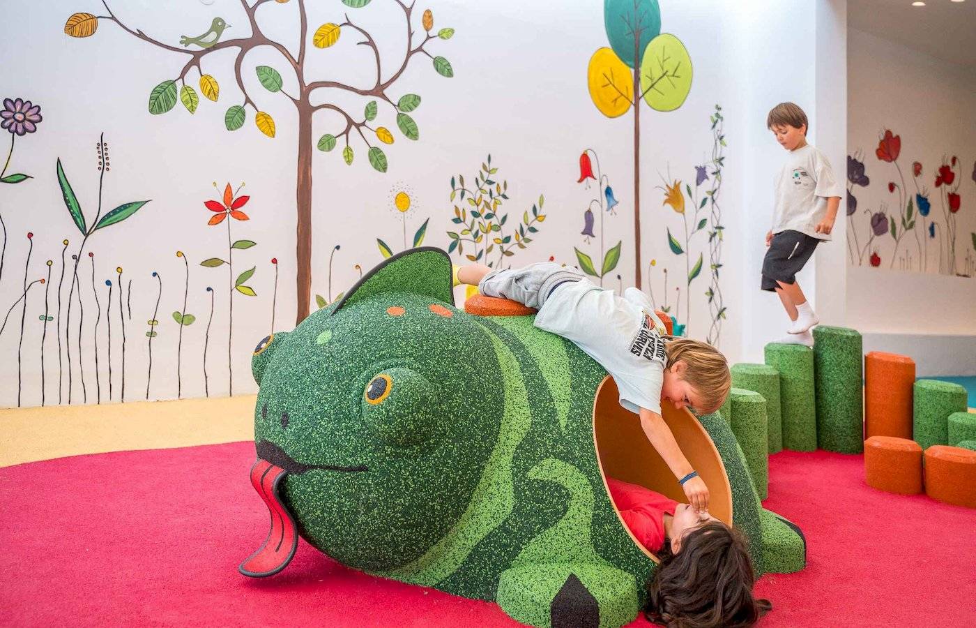 Kinder spielen in einem grünen, fischförmigen Spielbereich im Arminda Hotel & Spa.