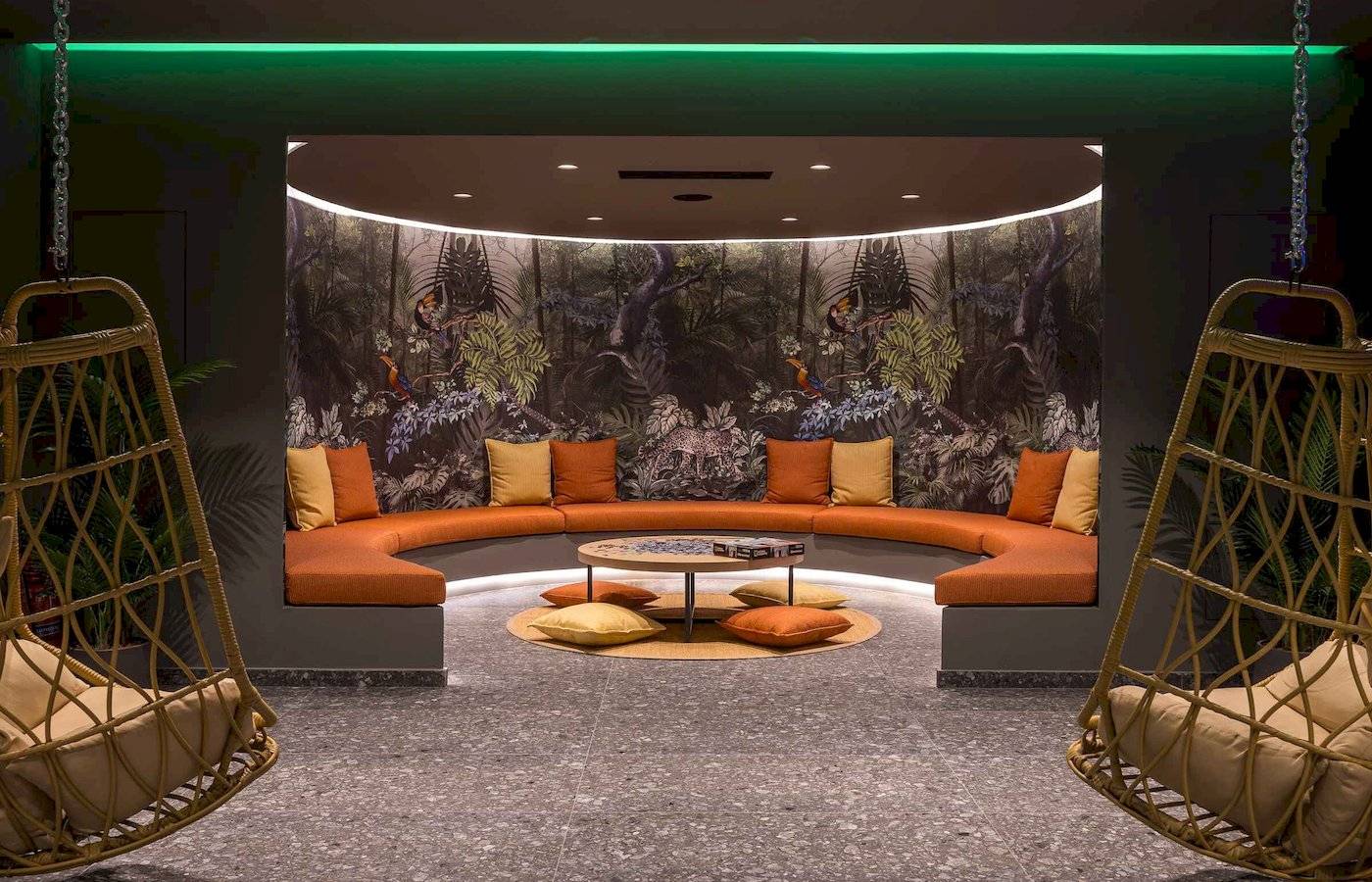 Loungebereich im Arminda Hotel & Spa mit geschwungenem Sofa und tropischem Wandbild.