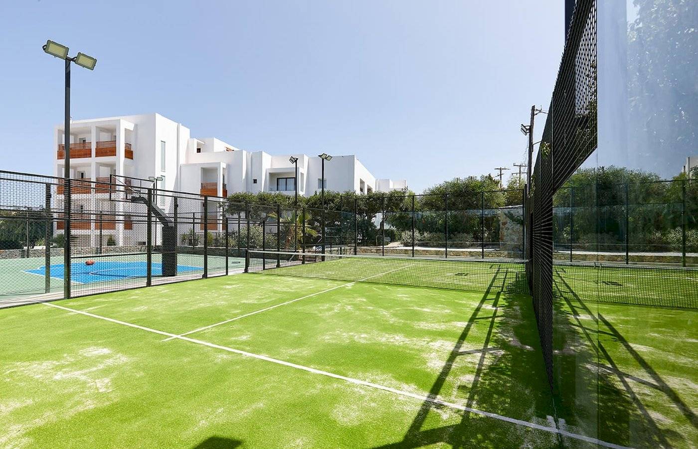 Tennisplatz vor dem Arminda Hotel & Spa mit grünem Kunstrasen und weißem Netz.