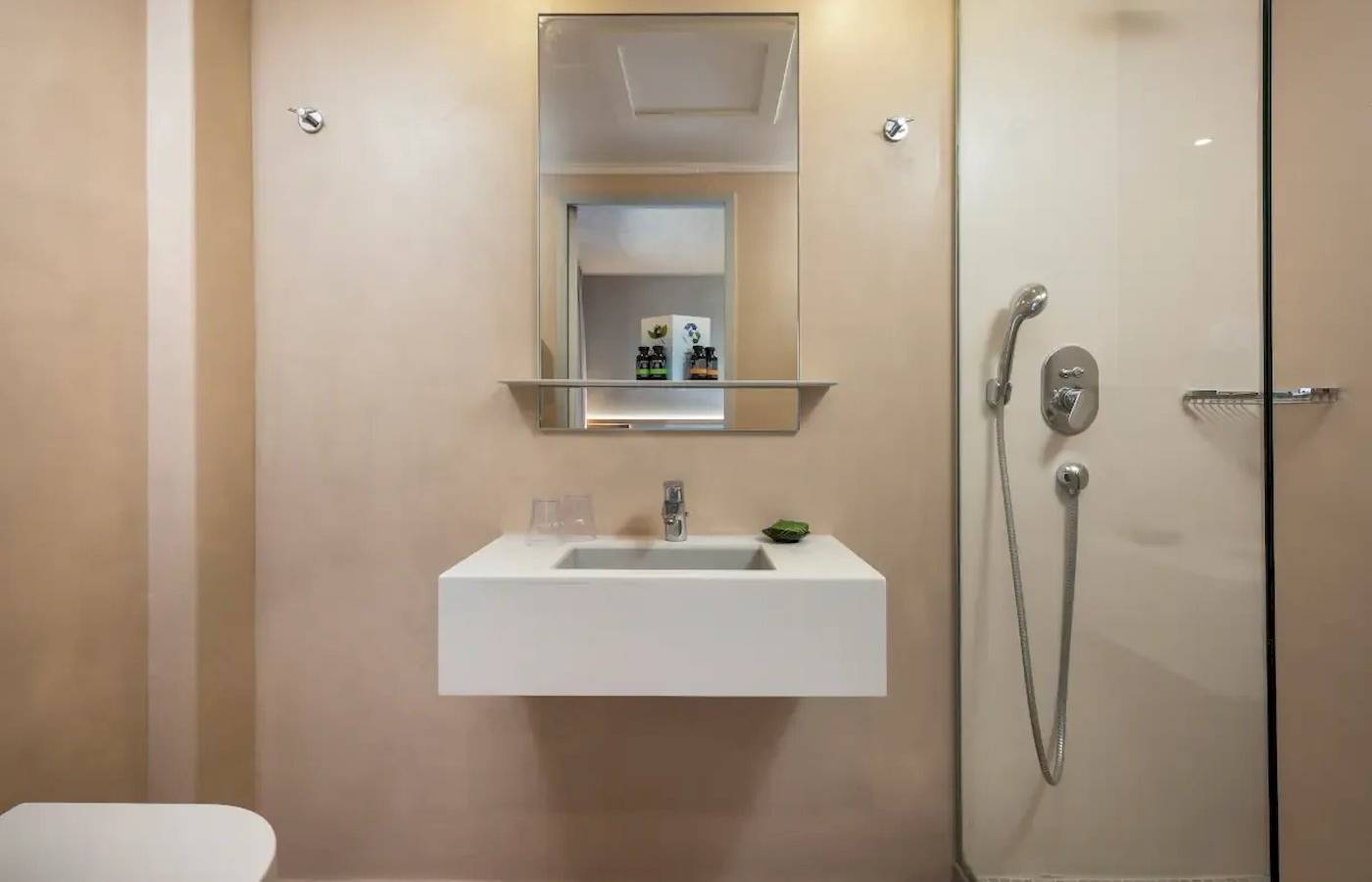 Badezimmer des Corissia Beach Hotels mit einer Duschkabine und einem Spiegel.