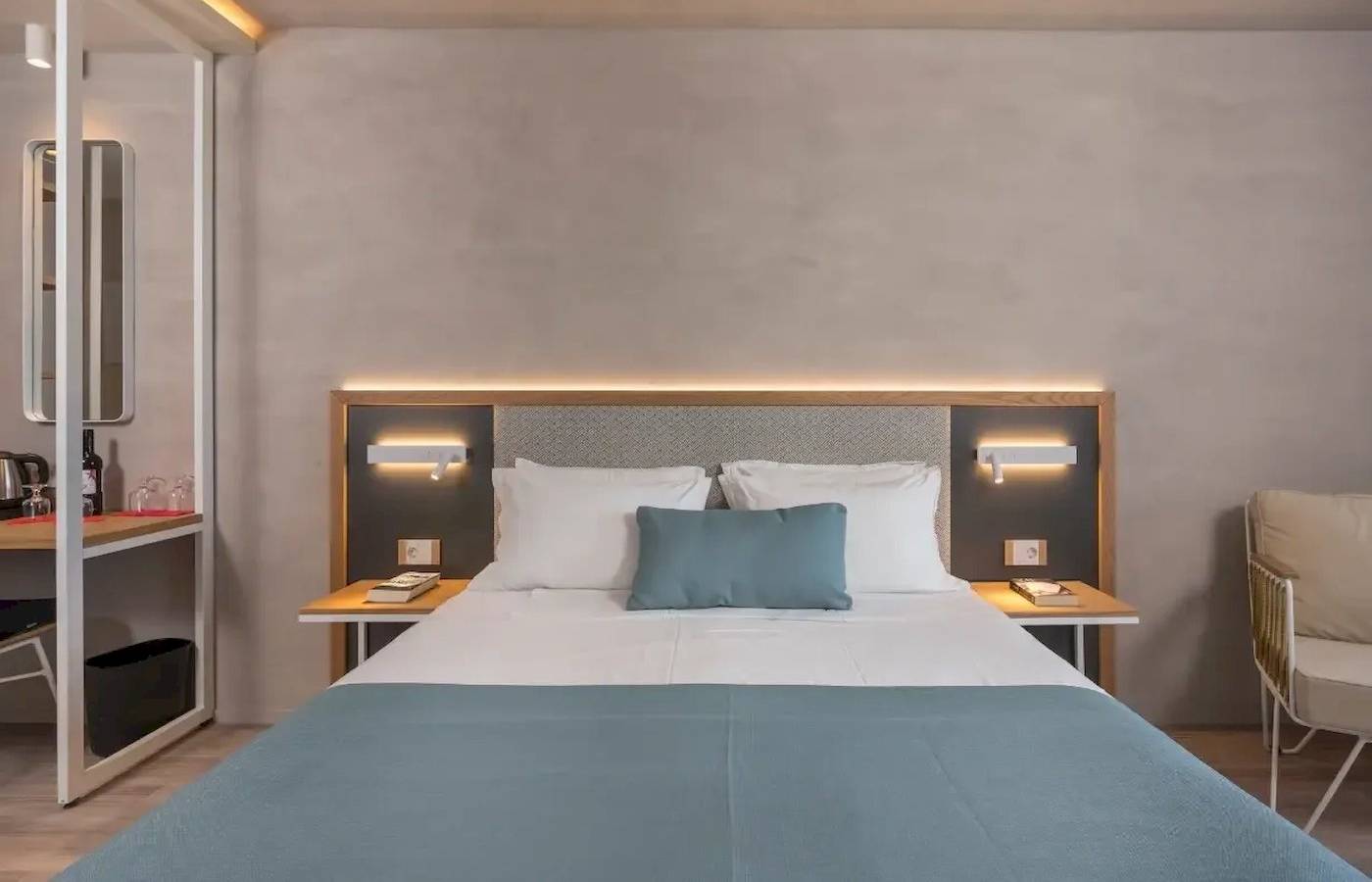 Schlafzimmer im Corissia Beach Hotel mit Bett, Kopfteilbeleuchtung und Nachttischen.