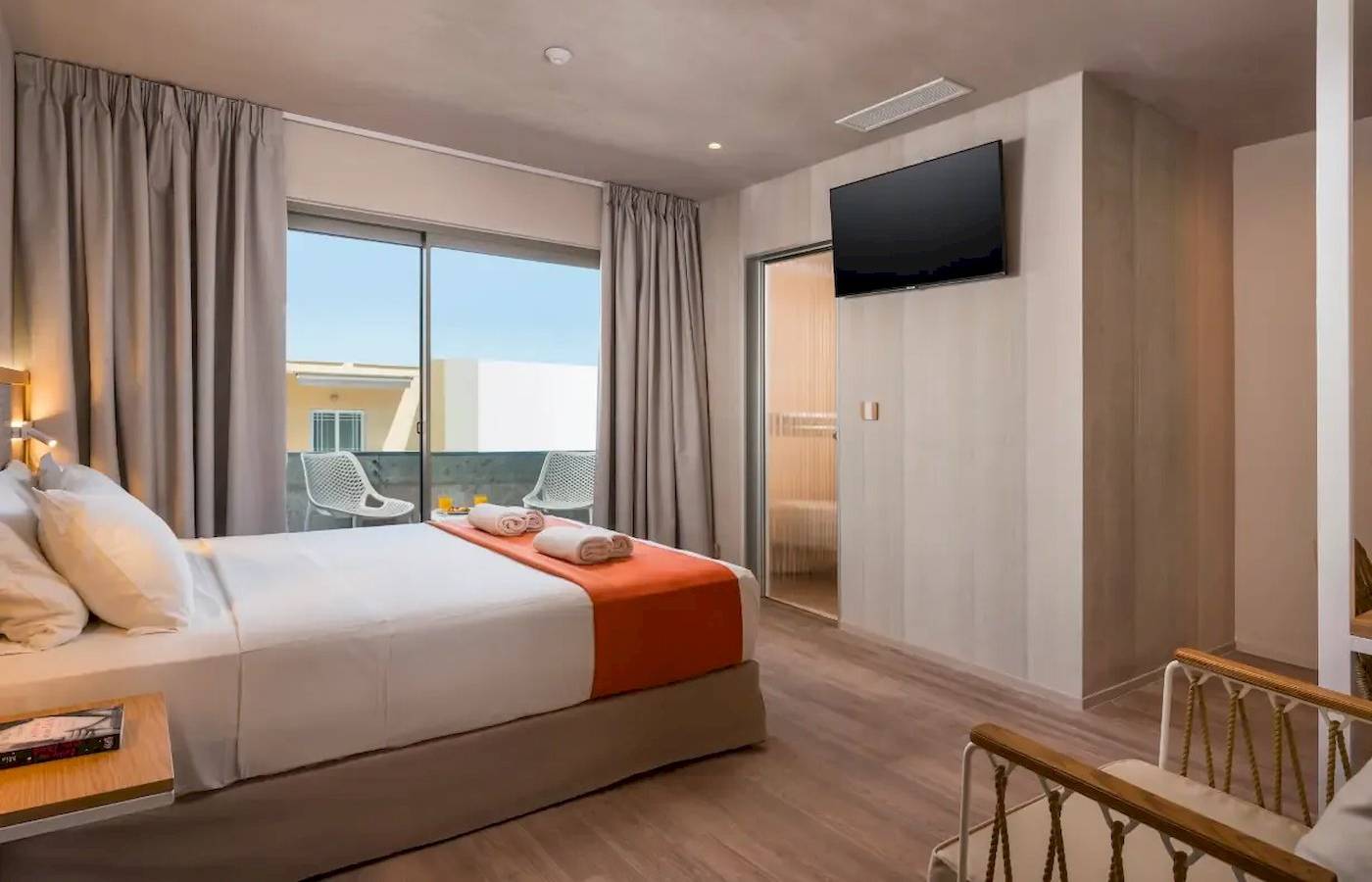 Innenansicht eines Doppelzimmers im Corissia Beach Hotel mit Bett, Fernseher und Balkon.