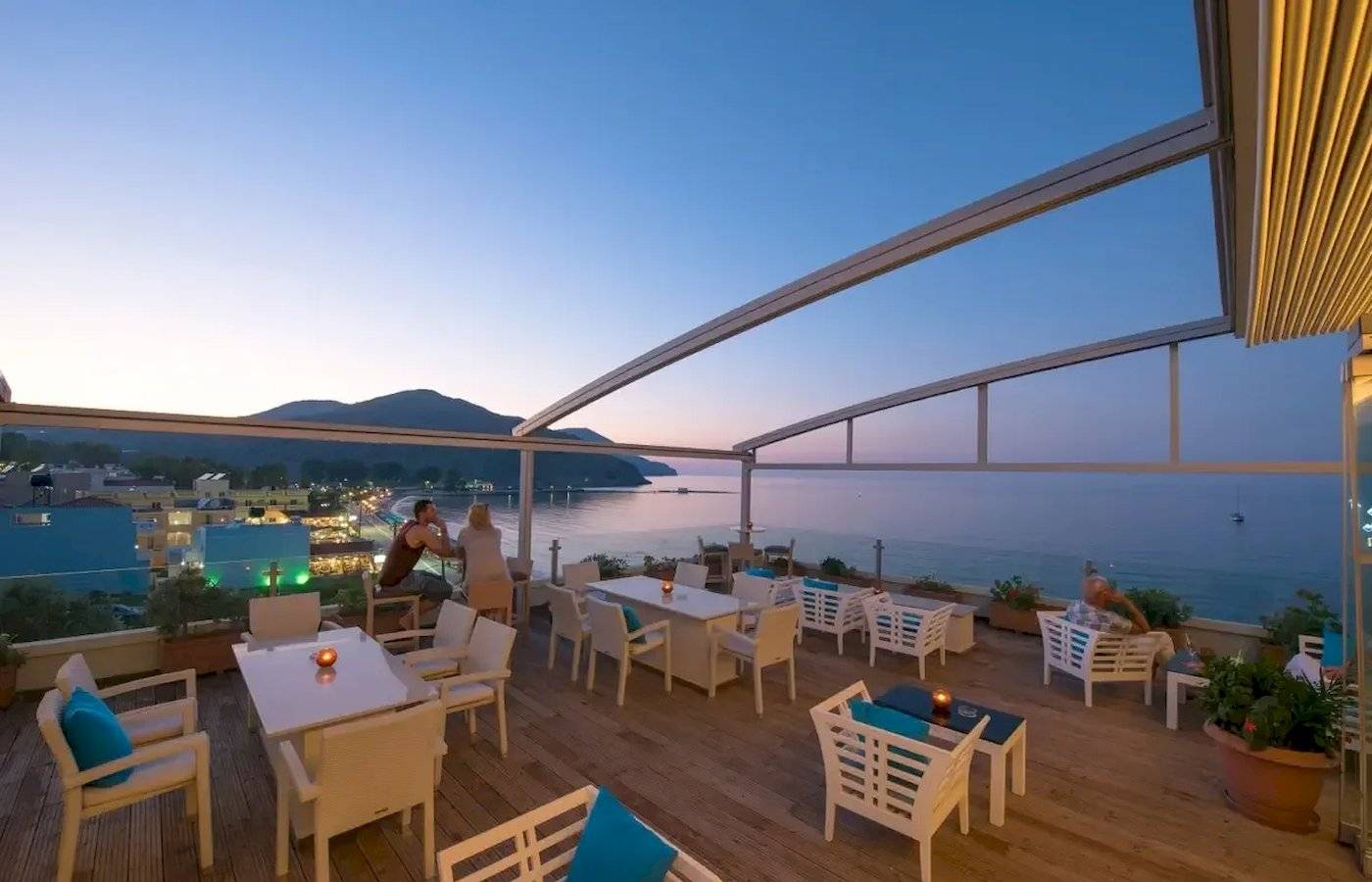 Abendliche Terrasse des Corissia Beach Hotels mit Blick auf das Meer und die Stadt.