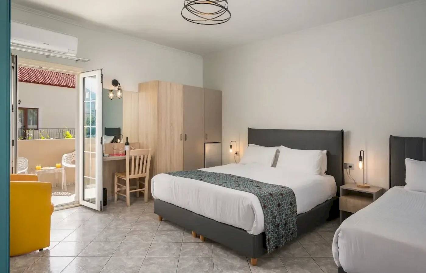 Doppelzimmer im Corissia Beach Hotel mit zwei Betten, Schreibtisch und Terrassenzugang.