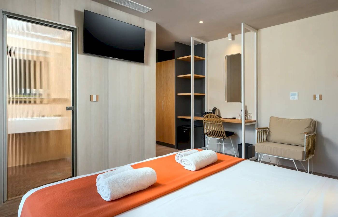 Innenansicht eines Zimmers im Corissia Beach Hotel mit Bett, Fernseher, Schreibtisch und Möbeln.