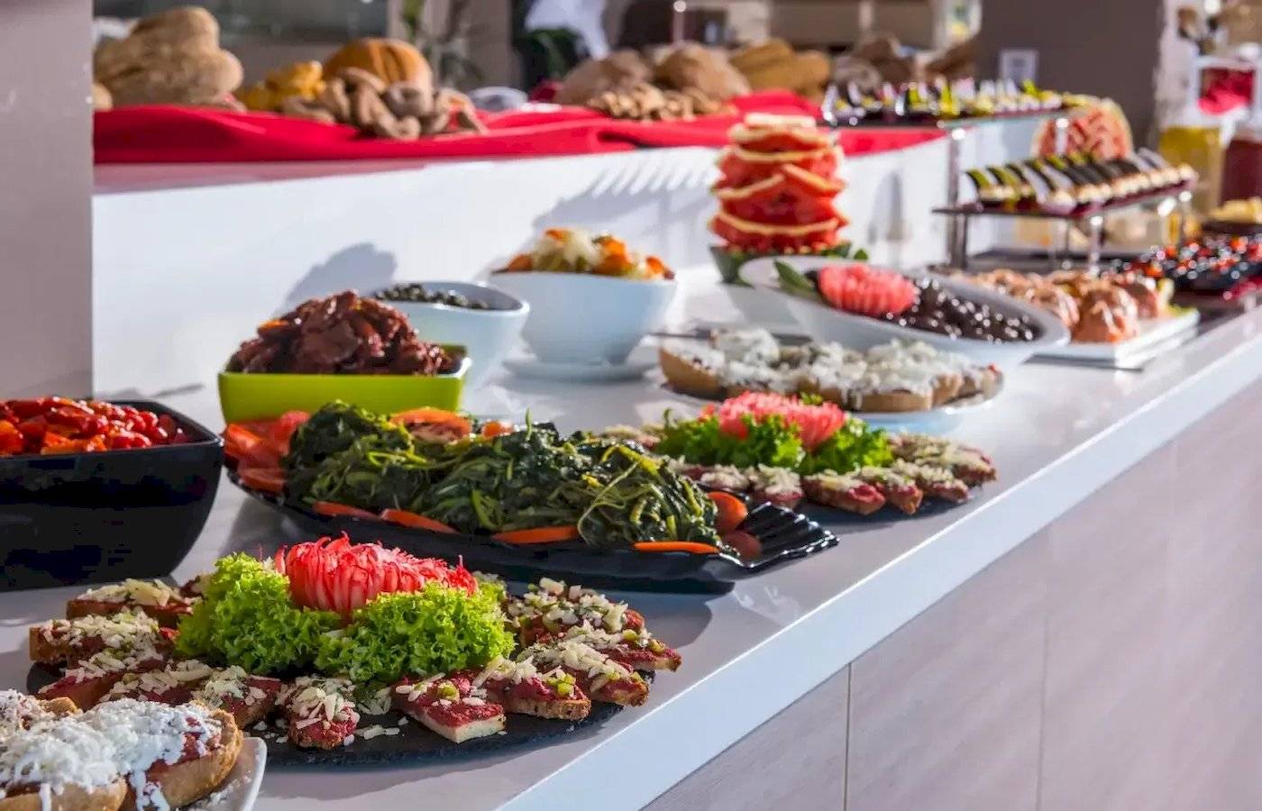 Buffet im Corissia Beach Hotel mit verschiedenen Speisen auf einem langen Tisch.
