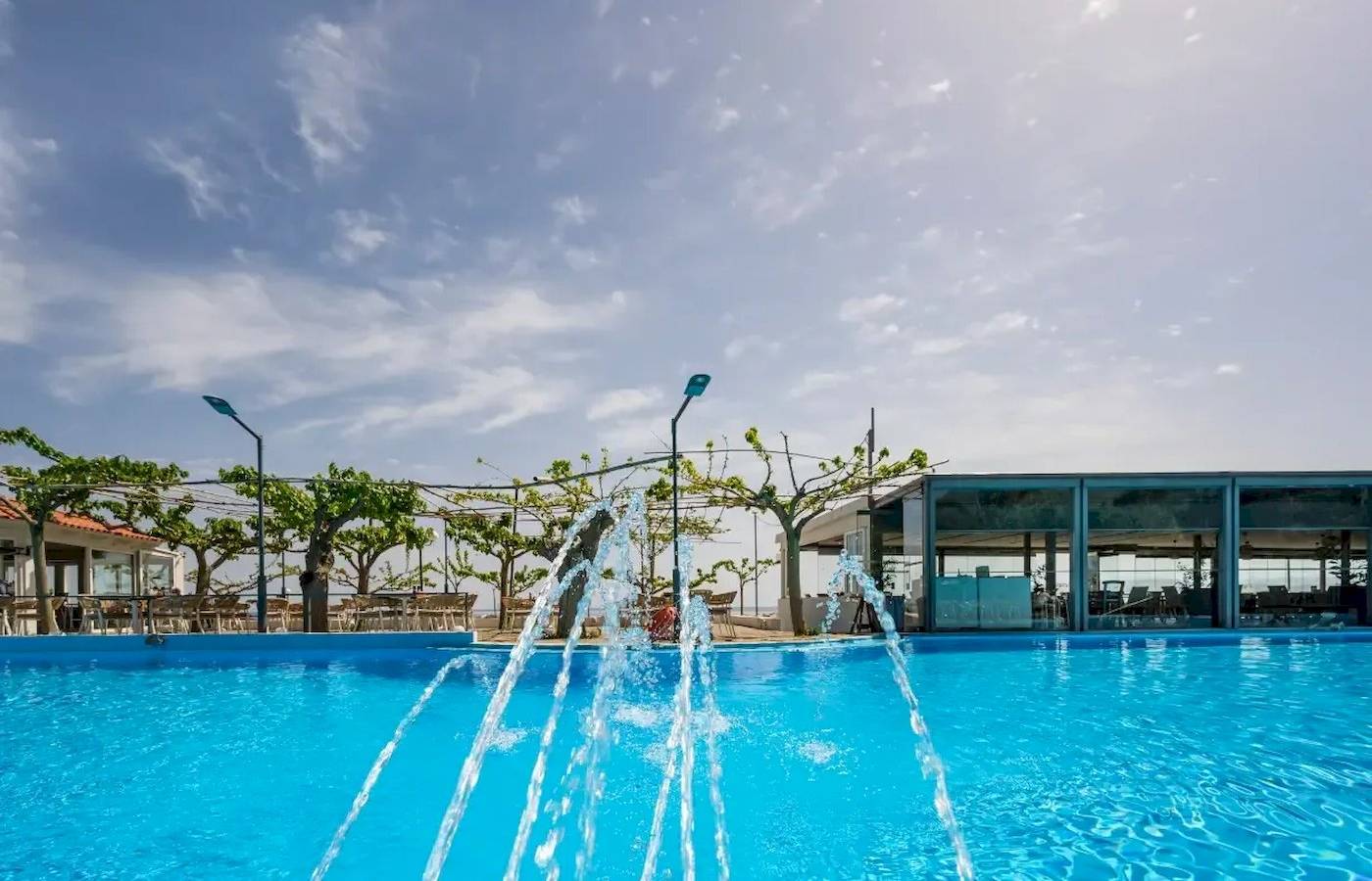 Außenpool des Corissia Beach Hotels mit Wasserspiel unter blauem Himmel