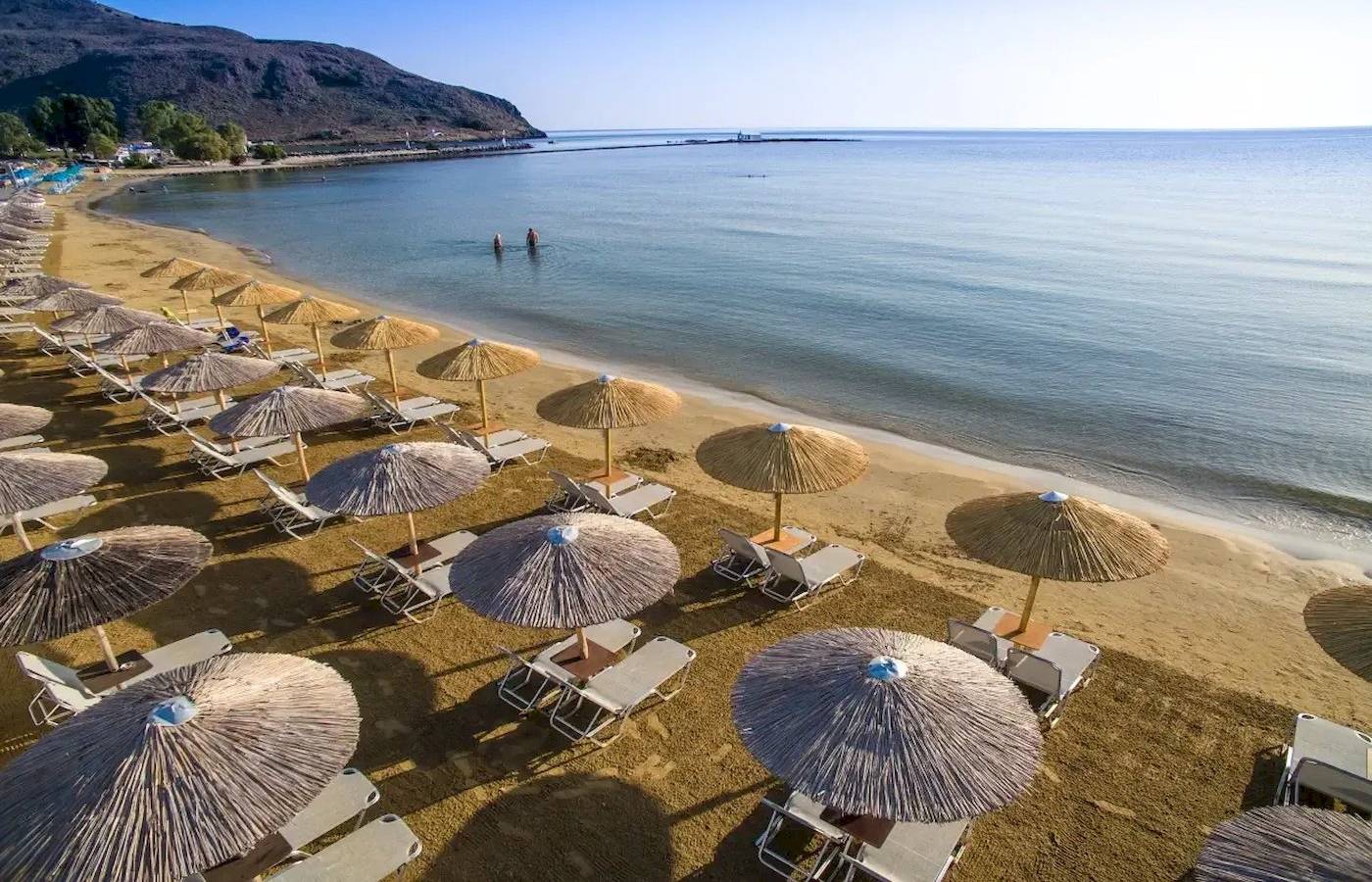 Luftaufnahme des Corissia Beach Hotels mit vielen Liegestühlen und Sonnenschirmen am Strand