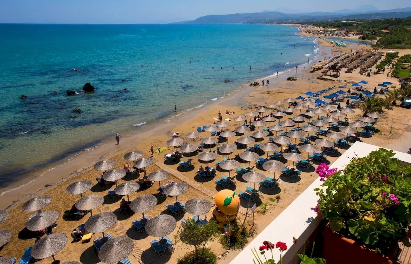 Luftaufnahme des Corissia Beach Hotels mit Sonnenterrasse und vielen Sonnenschirmen am Strand