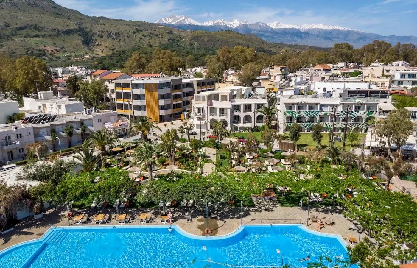 Corissia Beach Hotel mit Pool und Gebäuden vor einem Berg