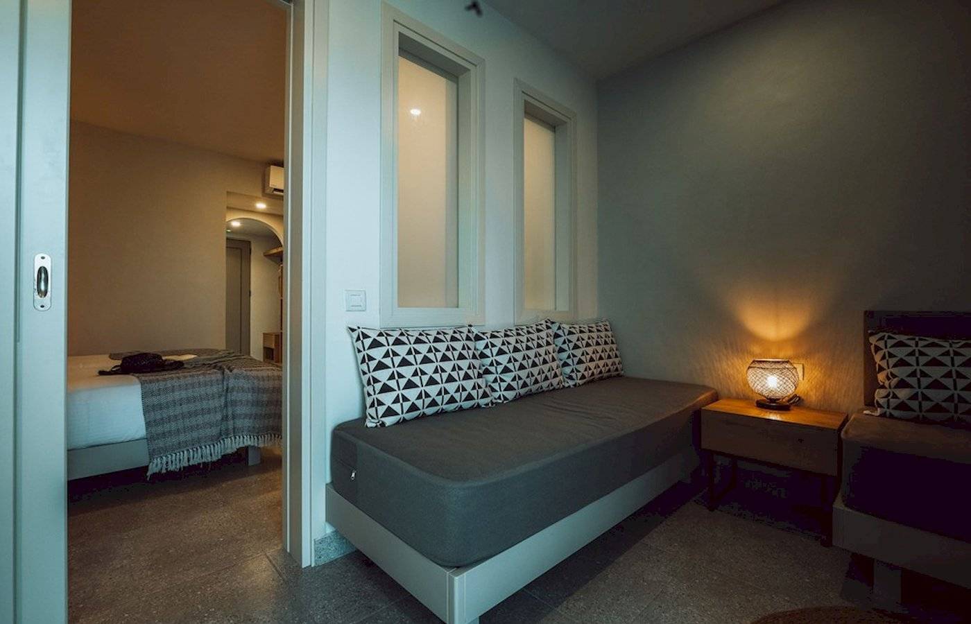 Schlafzimmer im Eliros Mare Hotel mit Sofabett, Nachttisch und Lampe.