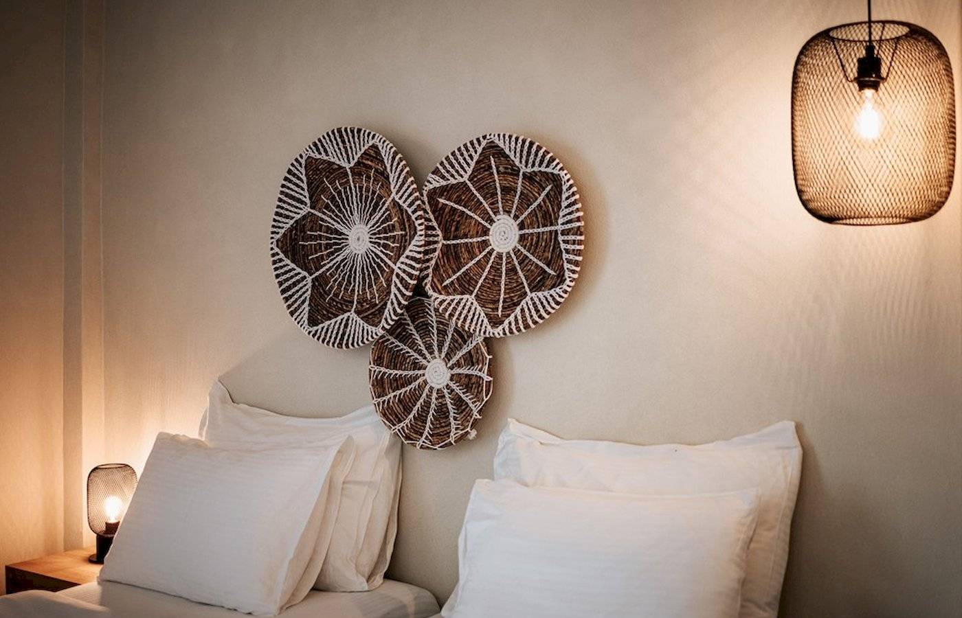 Schlafzimmer im Eliros Mare Hotel mit zwei Betten, weißen Kissen und dekorativen Wandkörben.