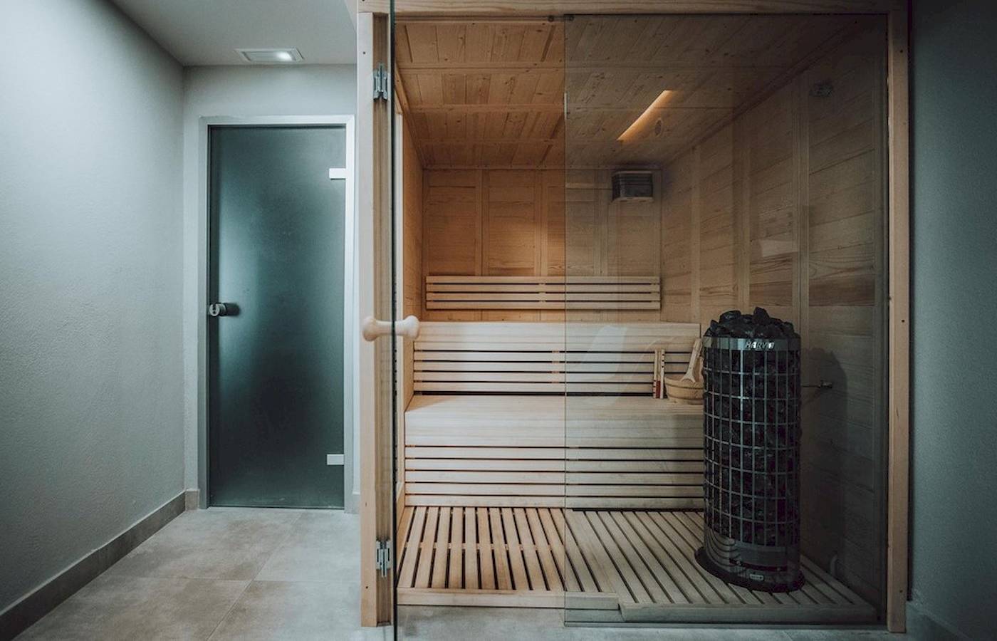 Eine hölzerne Sauna mit offenem Eingang und einer Heizeinheit in einem modernen Hotel.