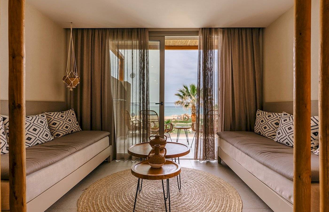 Innenraum des Eliros Mare Hotels mit Blick auf das Meer und einem Wohnzimmer mit zwei Sofas und Tisch.