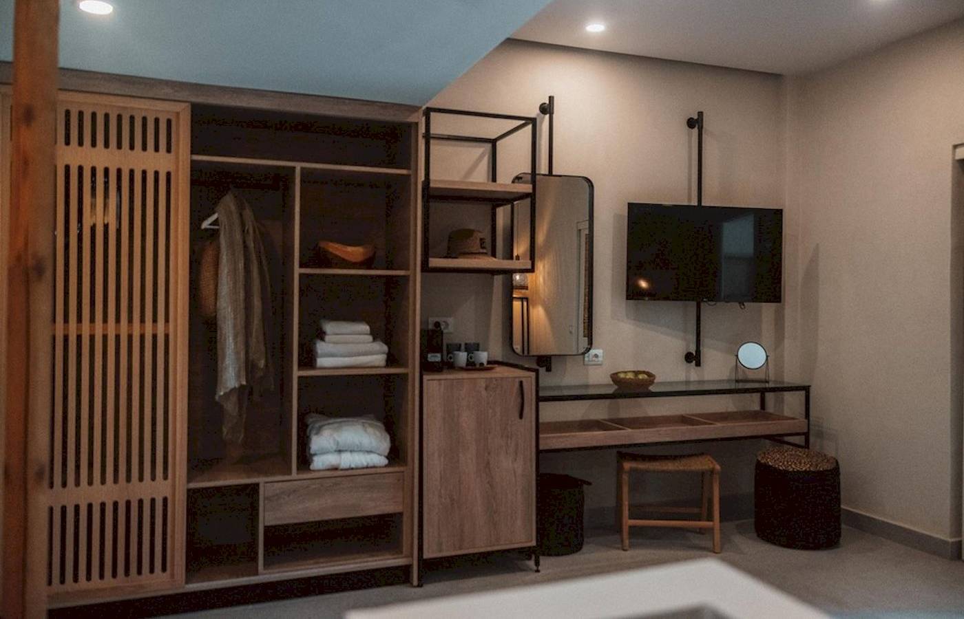 Innenansicht eines Zimmers im Eliros Mare Hotel mit Kleiderschrank, Fernseher und Schreibtisch.