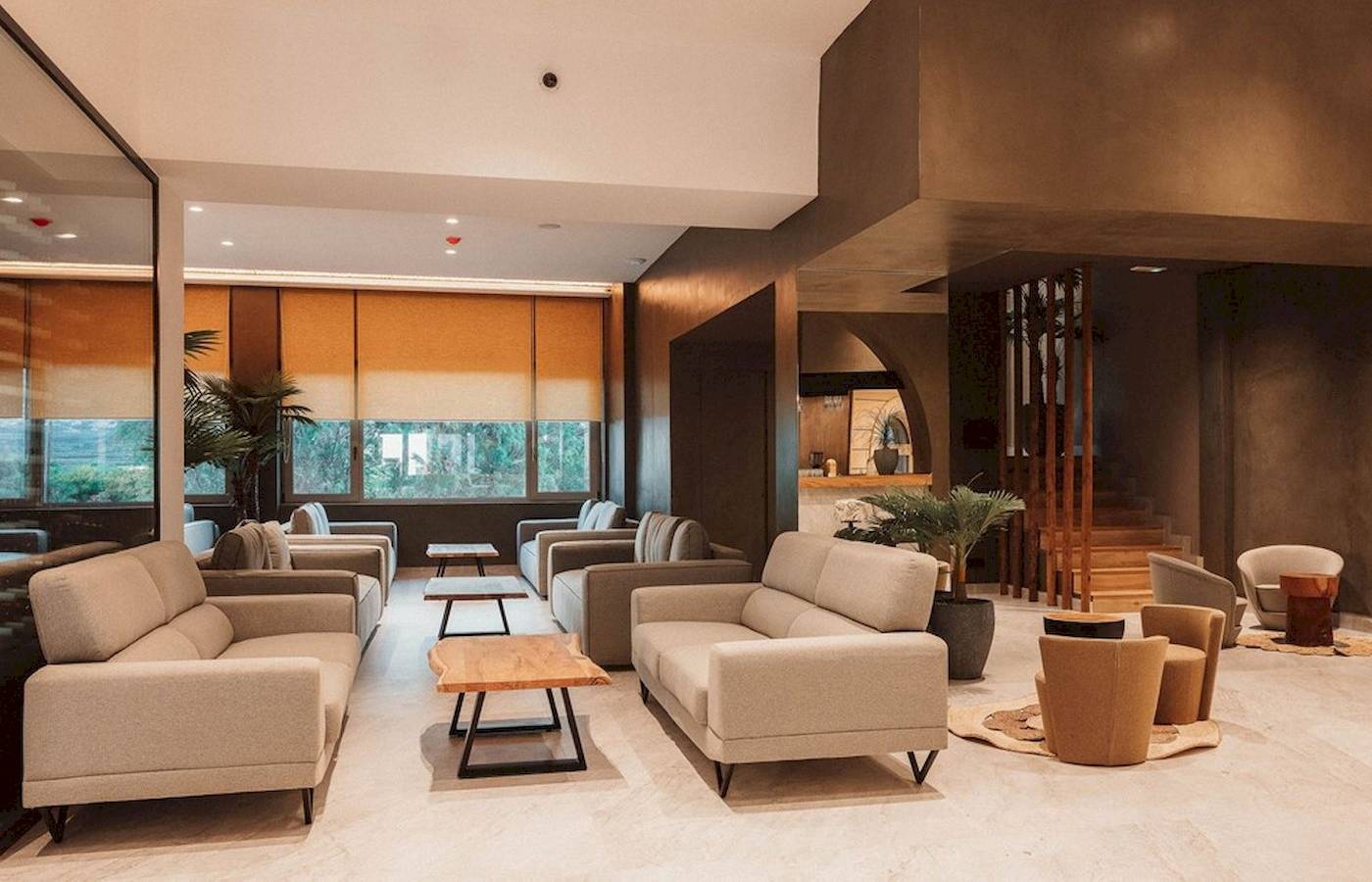 Innenansicht der Lobby des Eliros Mare Hotels mit modernen Möbeln, großen Fenstern und Pflanzen.