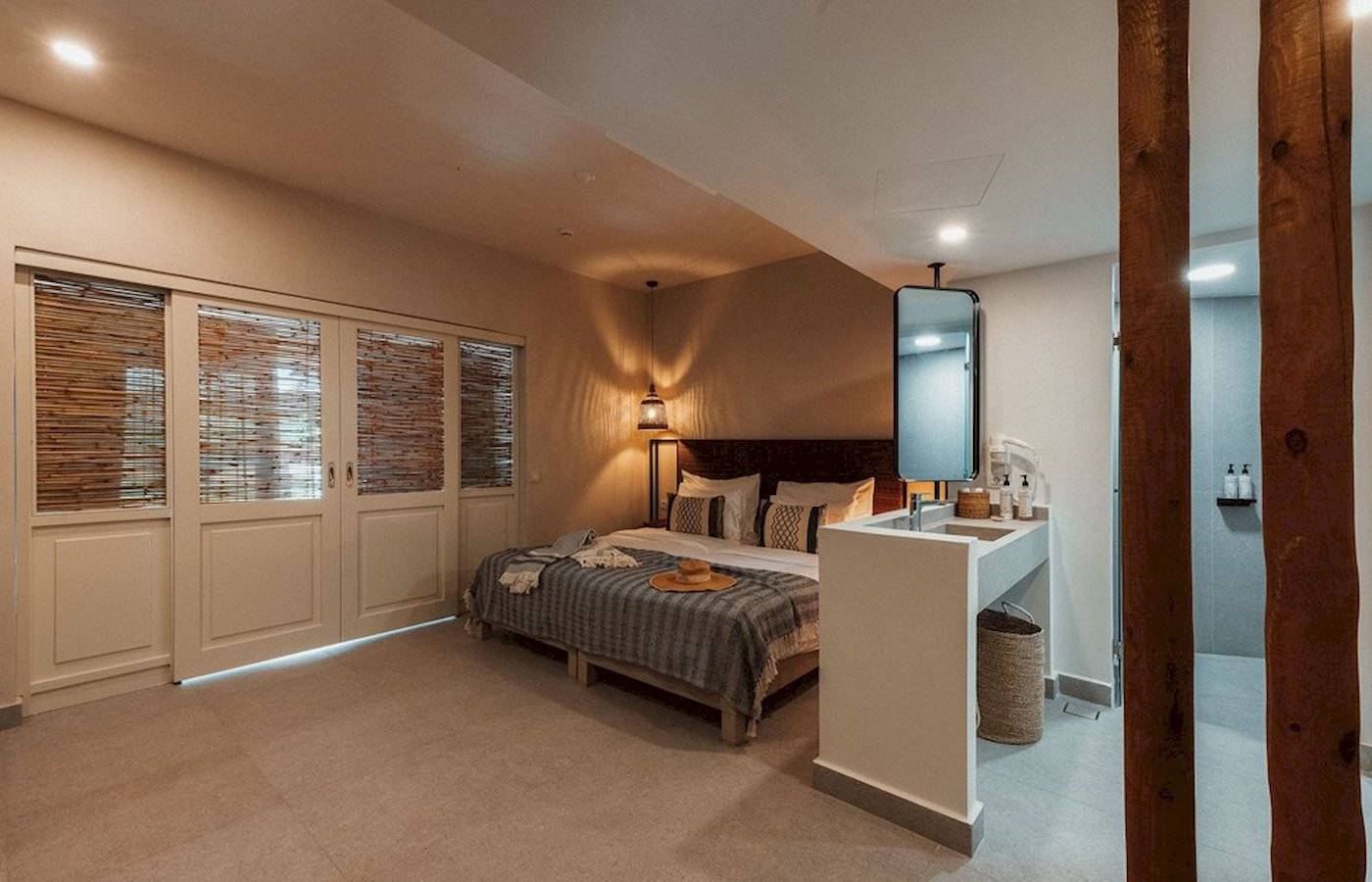 Innendesign eines Schlafzimmers im Eliros Mare Hotel mit Bett, Spiegel und Badezimmer.