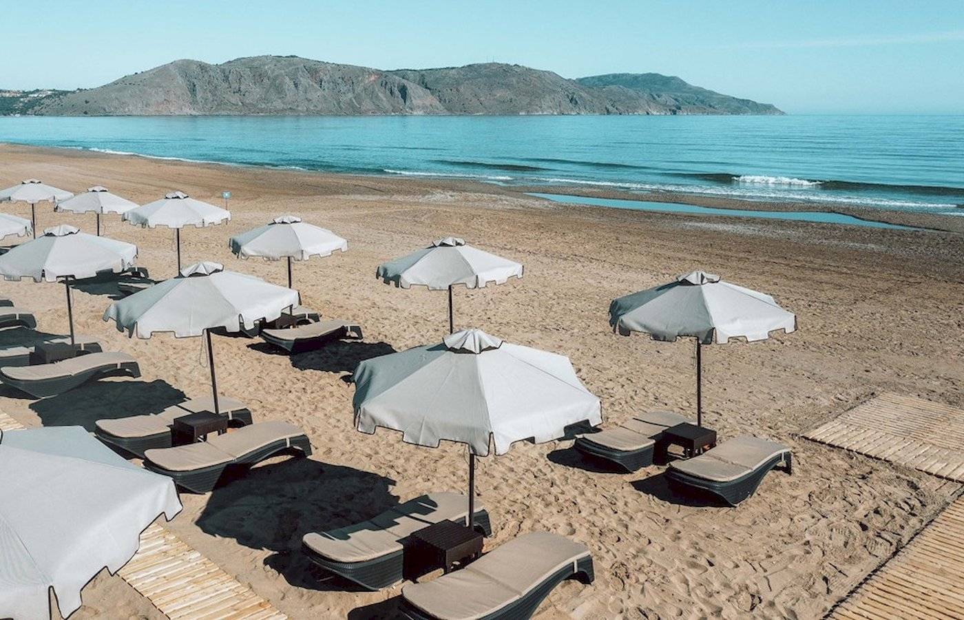 Strand des Eliros Mare Hotels mit Sonnenschirmen und Liegestühlen am Meer