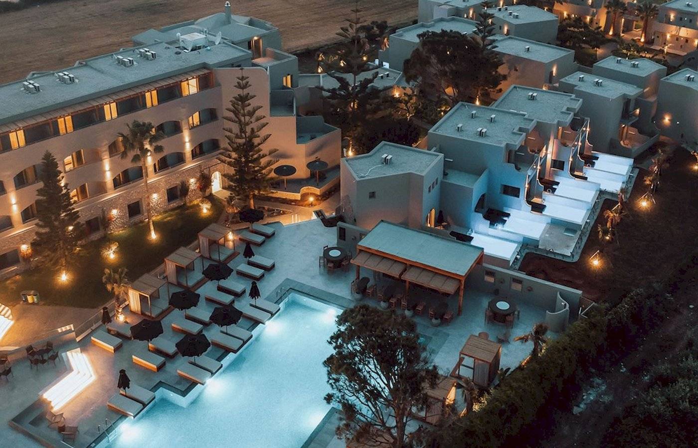 Luftaufnahme des Eliros Mare Hotels bei Nacht mit Pool und Beleuchtung.