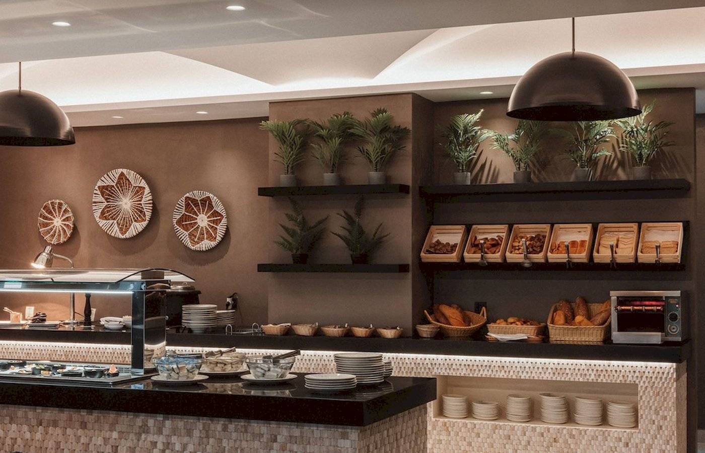 Frühstücksbuffet im Eliros Mare Hotel mit Speisen, Tellern und Pflanzen.