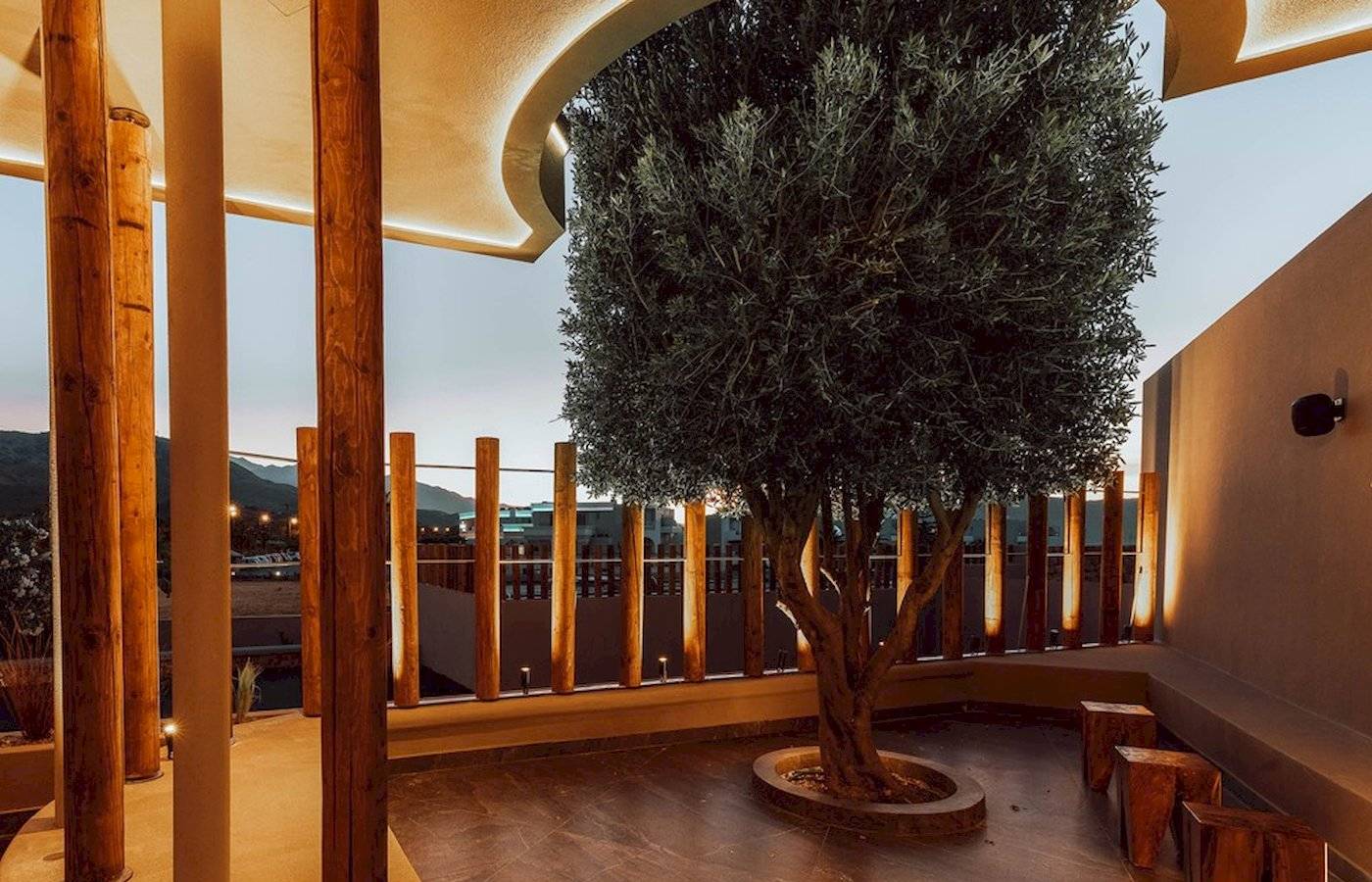 Außenterrasse des Eliros Mare Hotels mit einem großen Baum und hölzernen Stützen