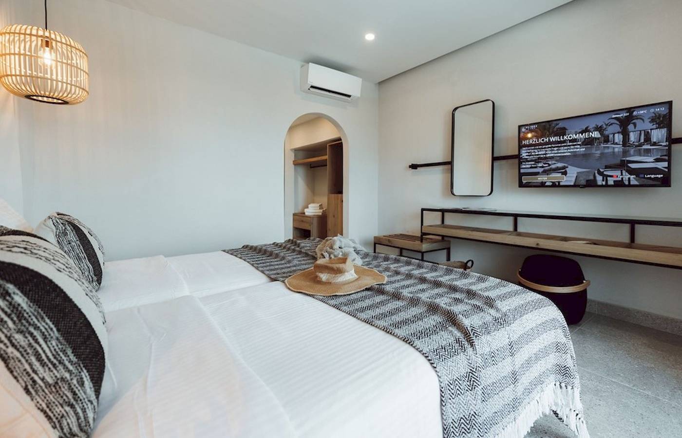 Schlafzimmer im Eliros Mare Hotel mit Bett, Fernseher, Spiegel und Wandmontage.