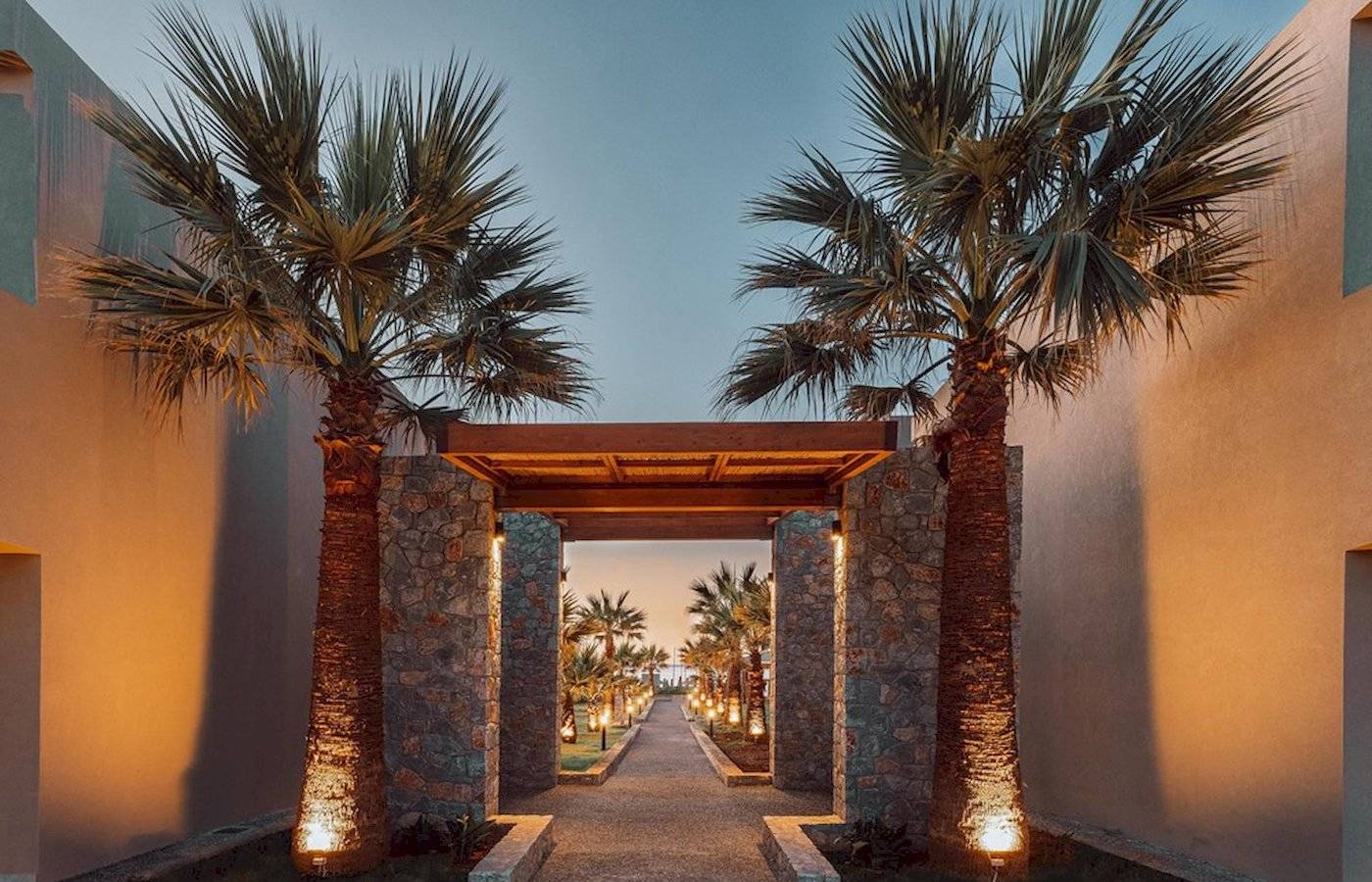 Eingang zum Eliros Mare Hotel mit Palmen und beleuchtetem Weg