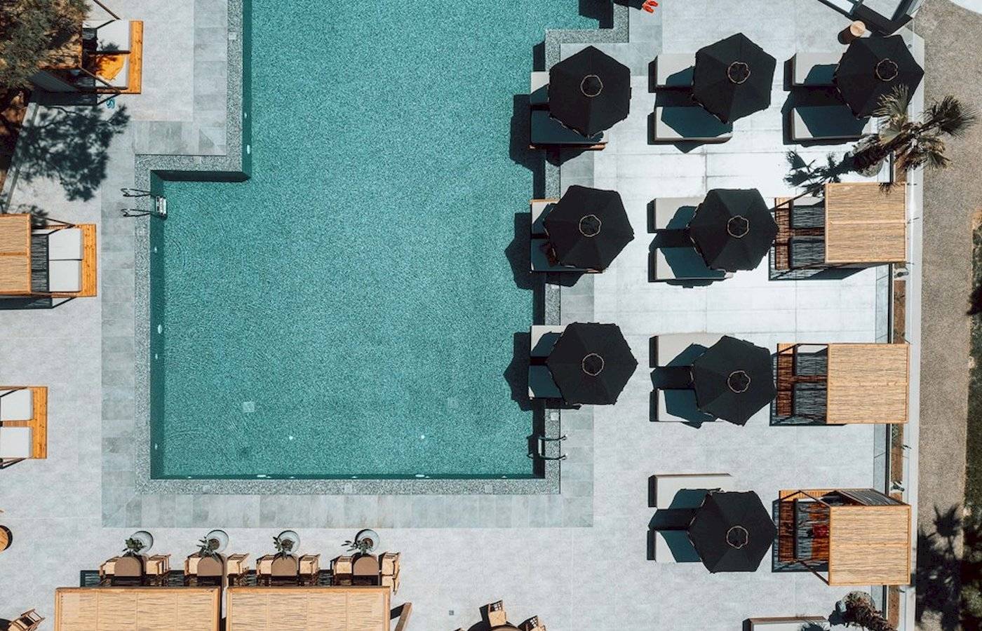 Luftbild vom Poolbereich des Eliros Mare Hotels mit Liegestühlen und Sonnenschirmen.