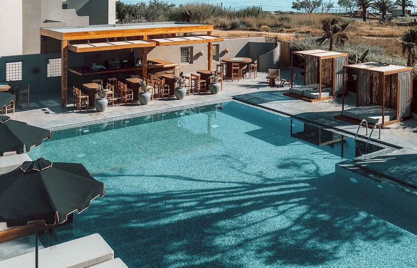 Außenbereich des Eliros Mare Hotels mit Pool, Bar und Sonnenliegen.