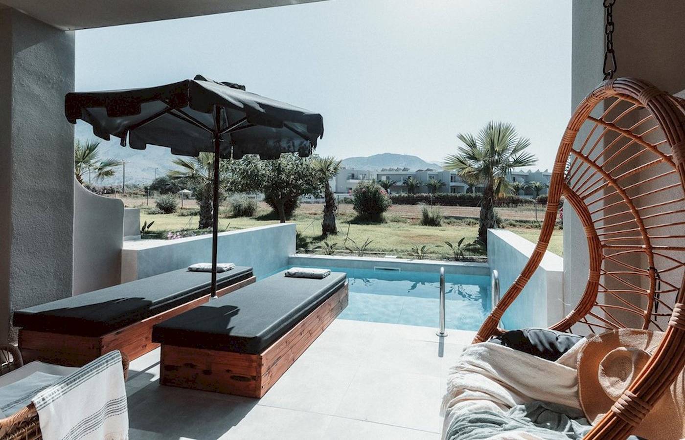 Terrasse mit Liegen und Umbrella beim Eliros Mare Hotel.