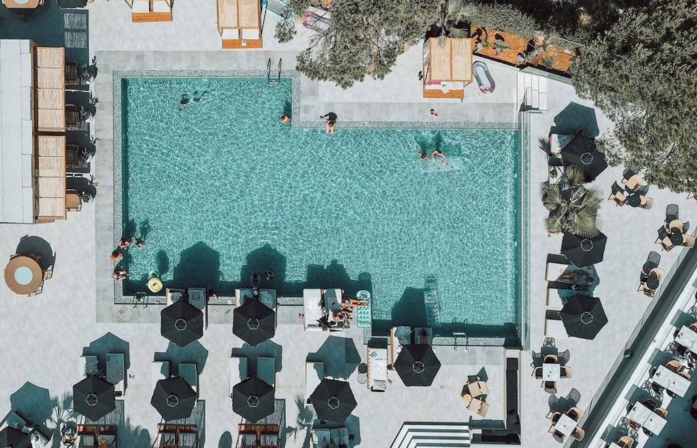 Luftaufnahme des Pools im Eliros Mare Hotel mit Gästen und Sonnenschirmen.