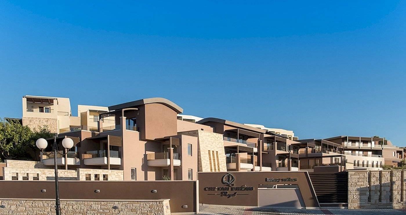 Haupteingang des Cretan Dream Resort & Spa mit mehreren Stockwerken und einem Logo