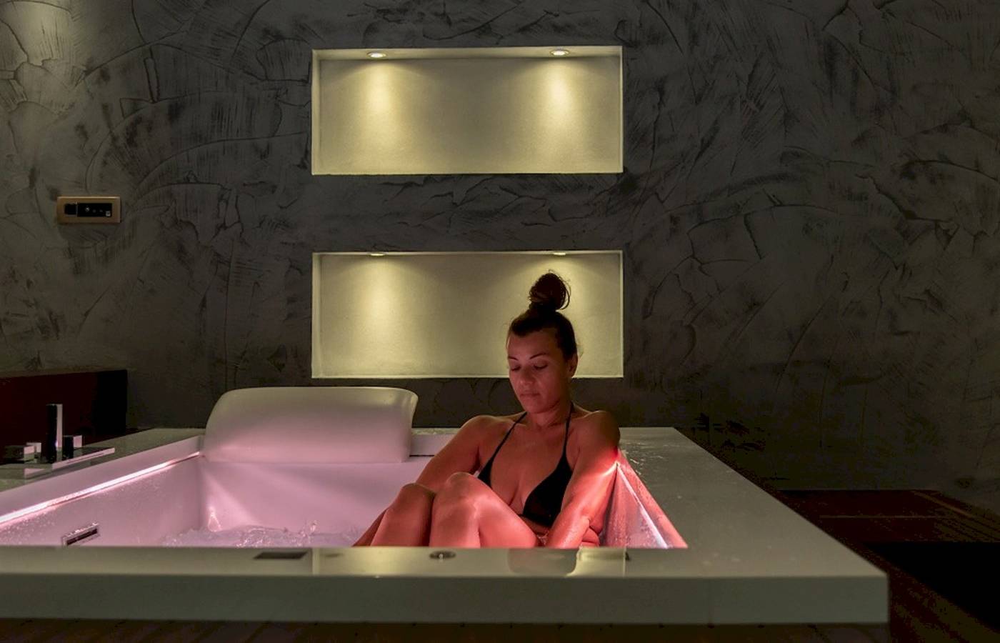 Frau in pink beleuchteter Badewanne