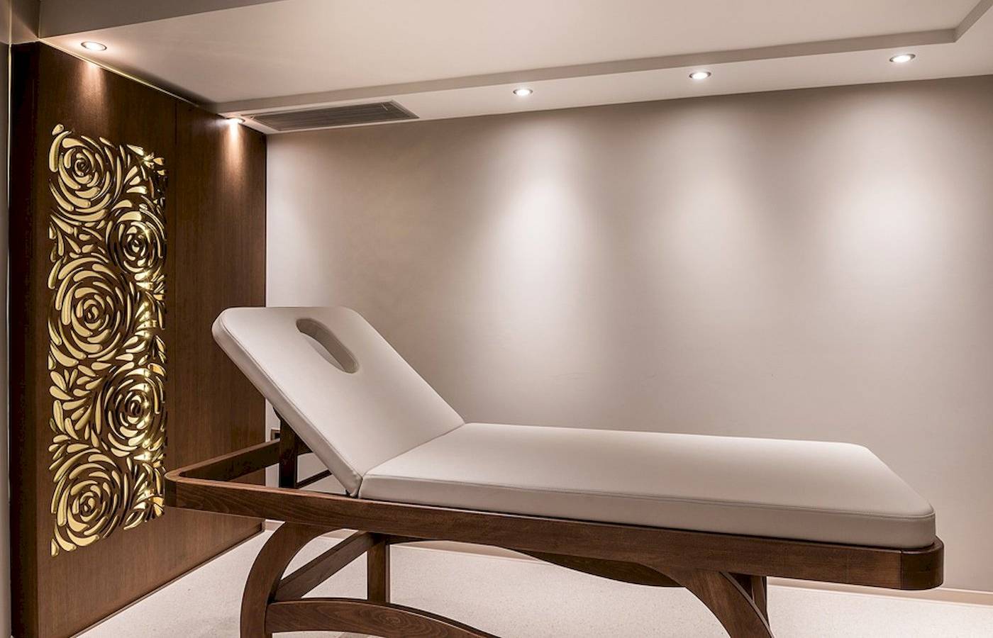 Behandlungsraum im Cretan Dream Resort & Spa mit weißer Liege und goldener Wandgestaltung