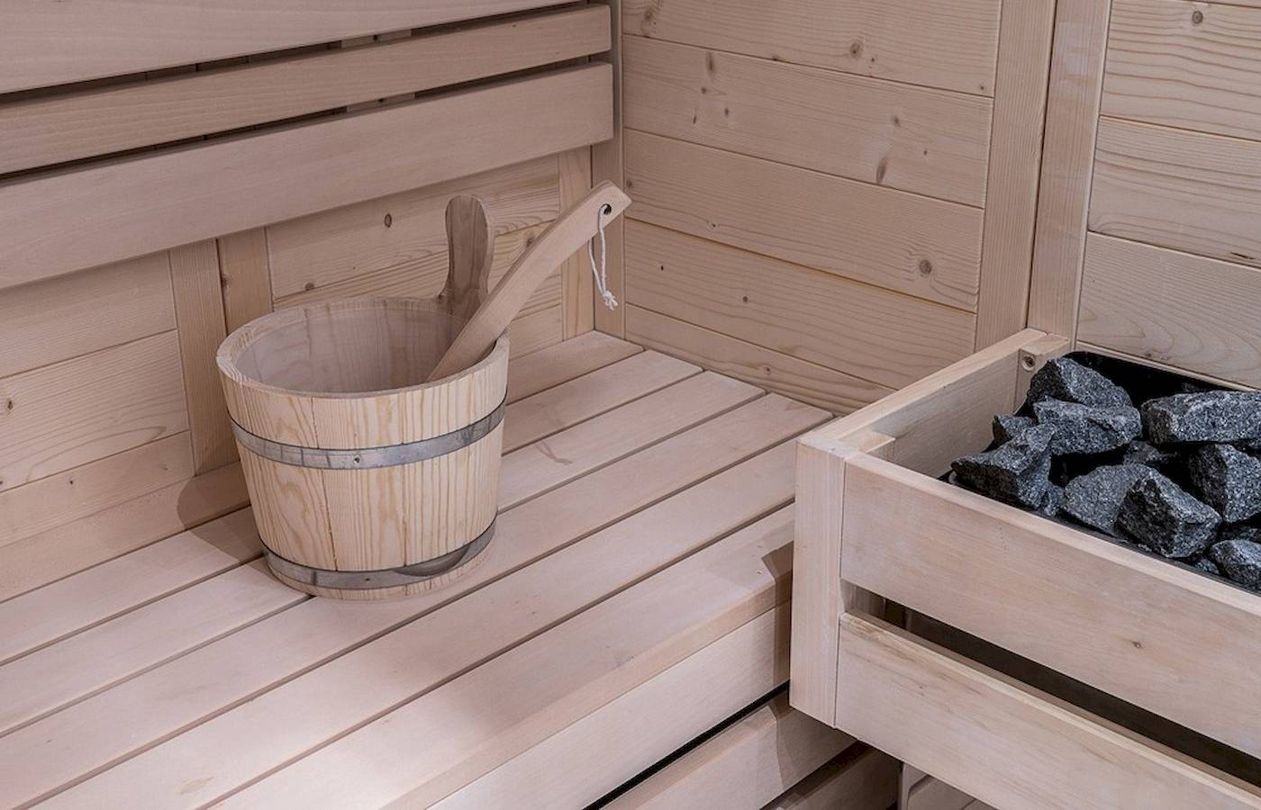 Innenraum einer Holzsauna mit einem Eimer und Steinen